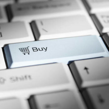 Close-up of a computer keyboard with a highlighted blue Buy key showing a shopping cart icon